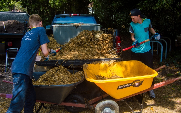 outward bound students shovel mulch into wheelbarrows during a service project with outward bound